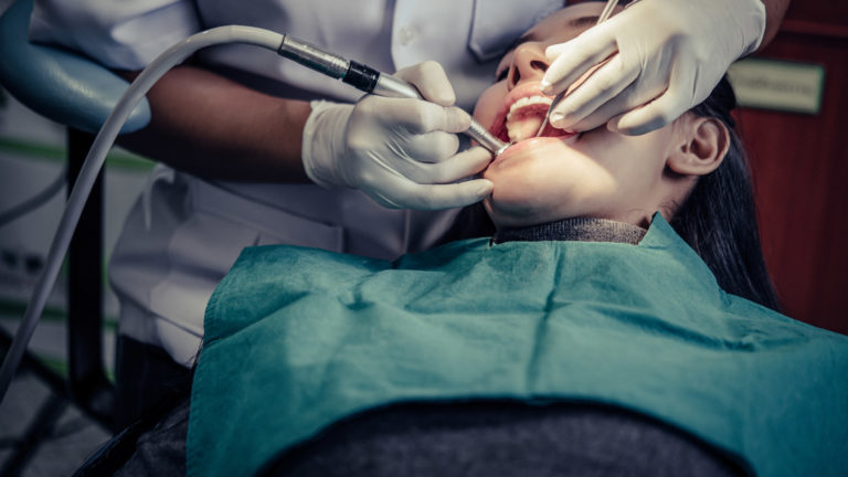 Dentist using a handpiece to treat a patient's front teeth