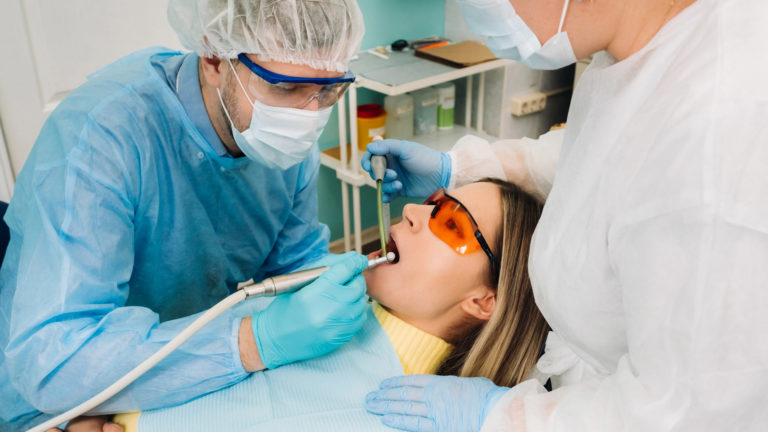 Dentist and assistant cleaning a patient's teeth during a preventive visit